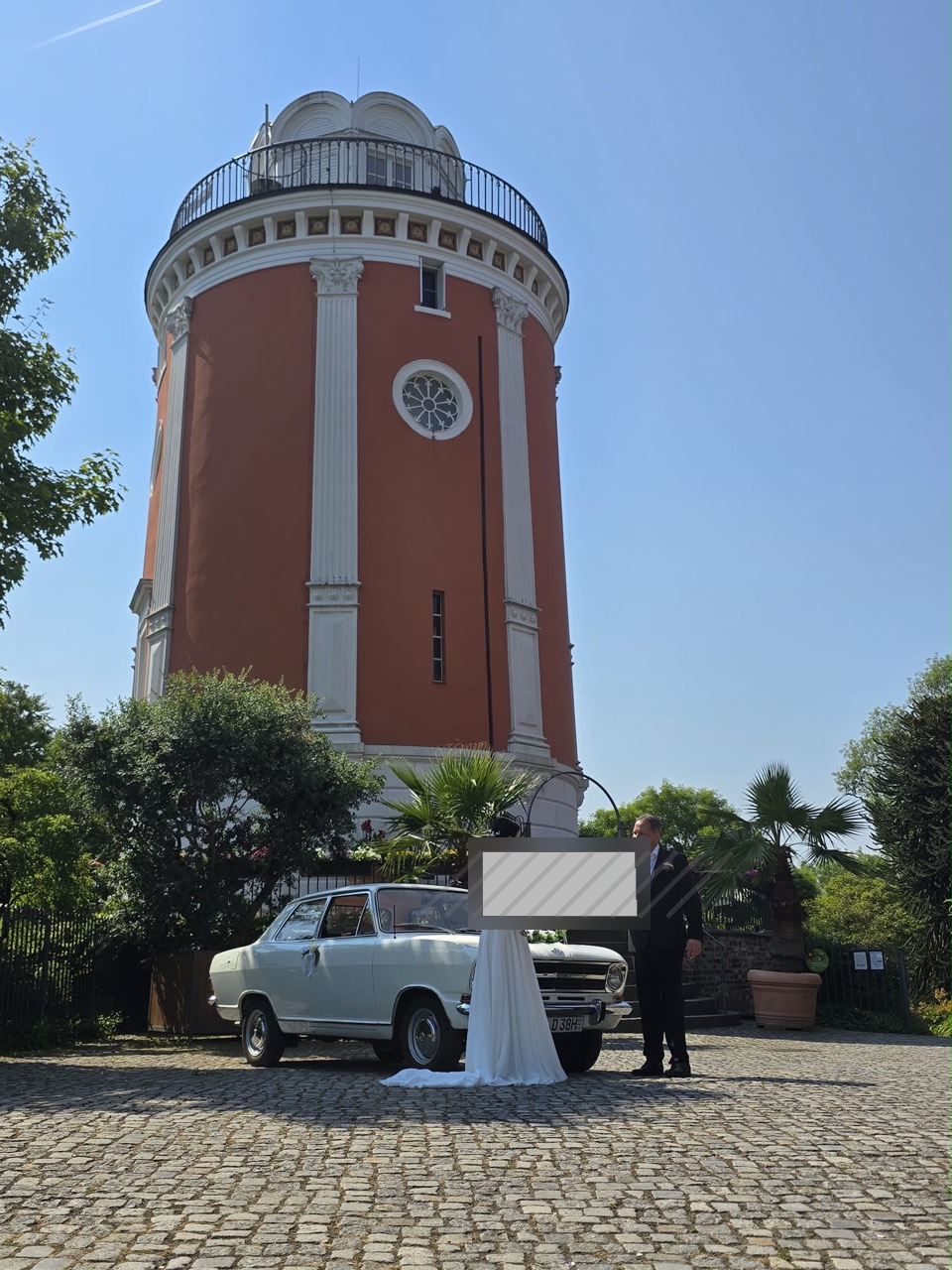 Brautpaar mit weißem Opel Kadett vor historischem Wasserturm